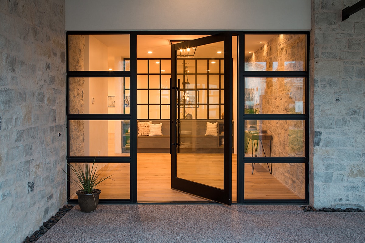 A massive pivot door encased by fixed windows greets visitors to the dramatic front entry.