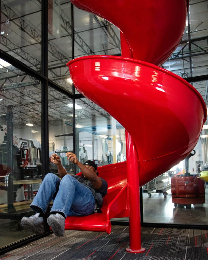 An employee sliding down a red, twisting slide.