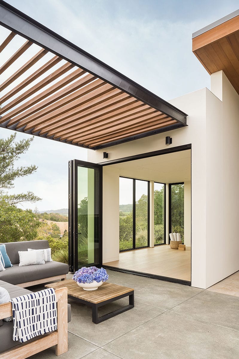 An open bi-fold door leads to a yoga room with floor-to-ceiling windows.