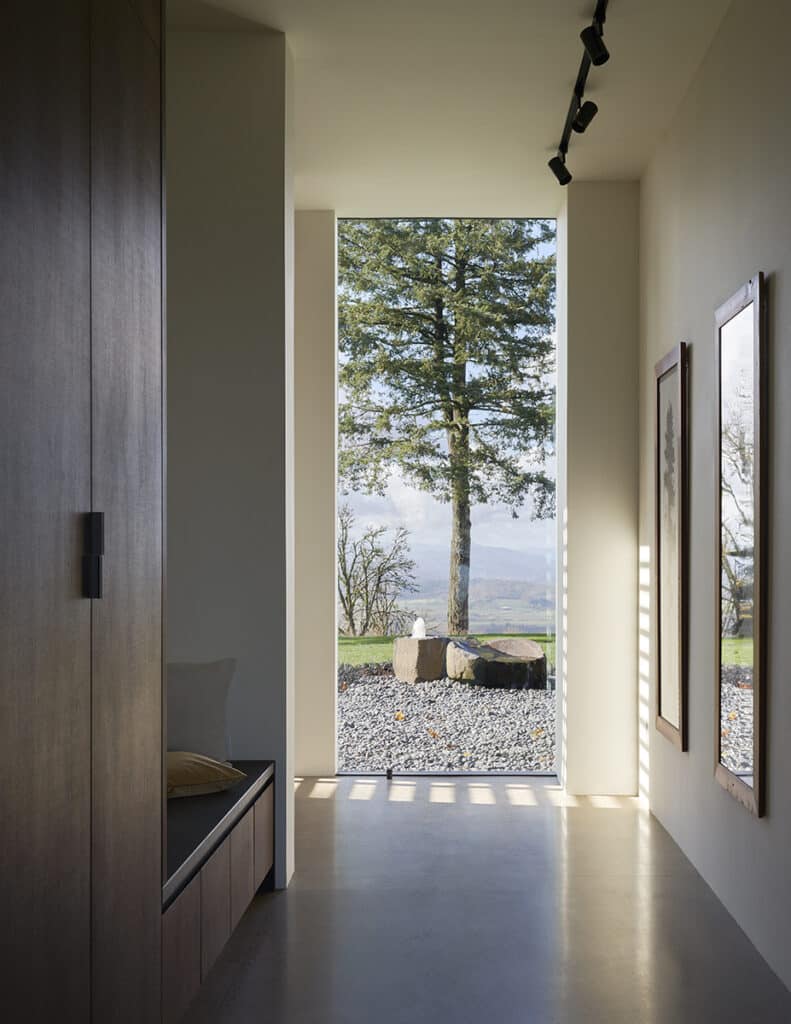 A tree is framed at the end of the hallway through a flush-framed window.