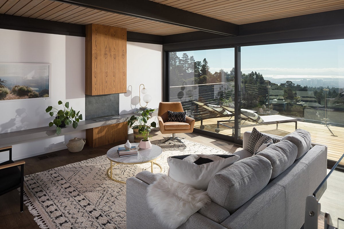 A living area features a large sliding glass door with a view of the city outside.