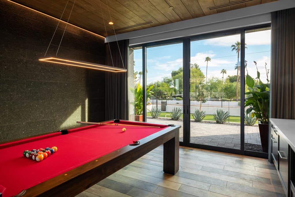 A billiards table faces a closed bi-parting sliding glass door.