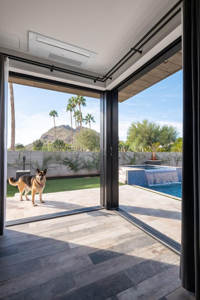 A view of Camelback Mountain framed by the bedroom 90-degree sliding door configuration with the resident’s dog standing on the patio.