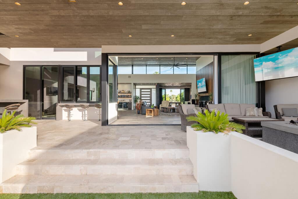 A view of the massive multi-slide door open, connecting the living room to the backyard and outdoor seating area.