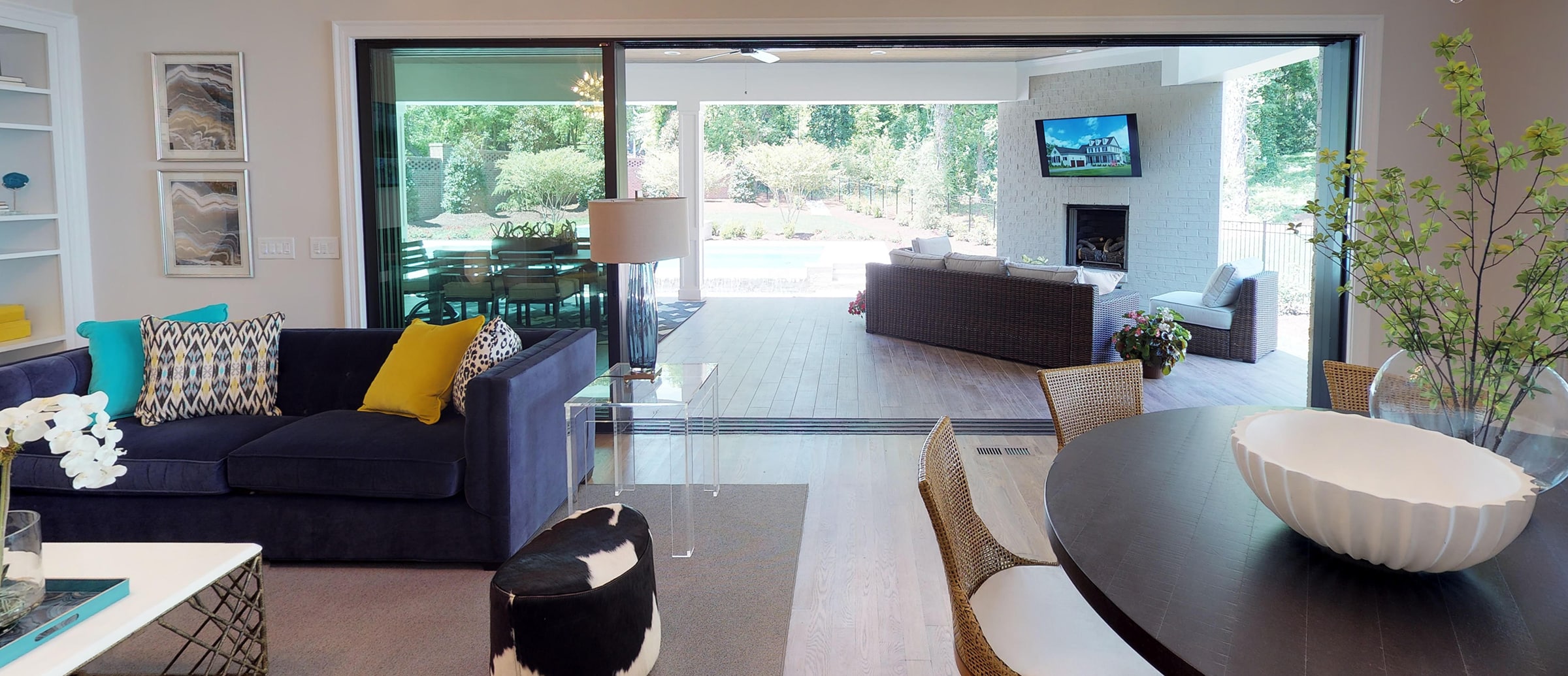 An open multi-slide glass door in the living room allows for a smooth transition to a backyard seating area.