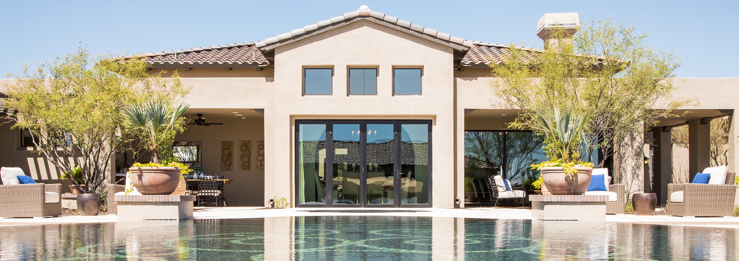 An outdoor pool is easily accessible from the back of a house via tall multi-slide glass doors.