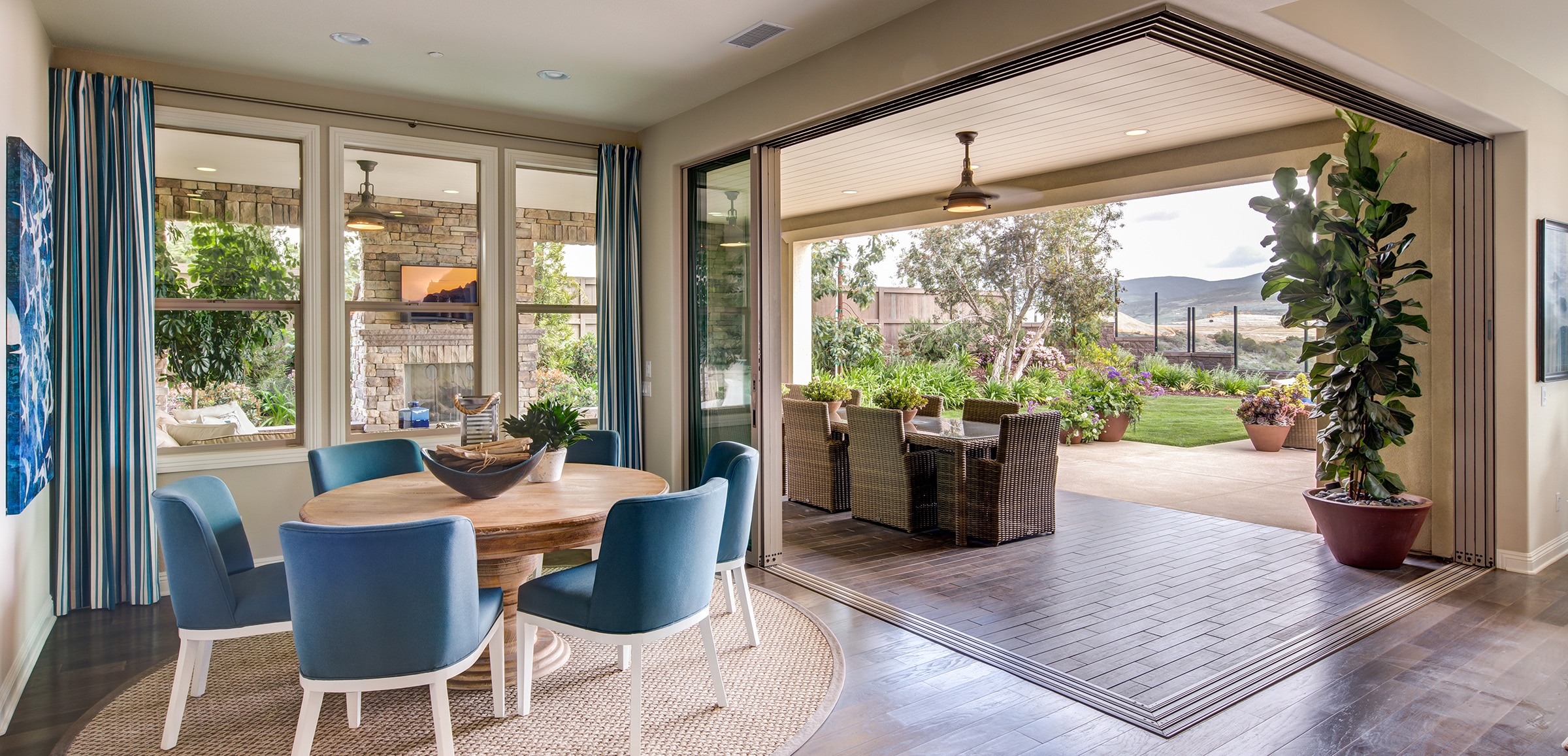 An indoor dining area seamlessly transitions to an outdoor dining area through pocketed multi-slide glass doors.