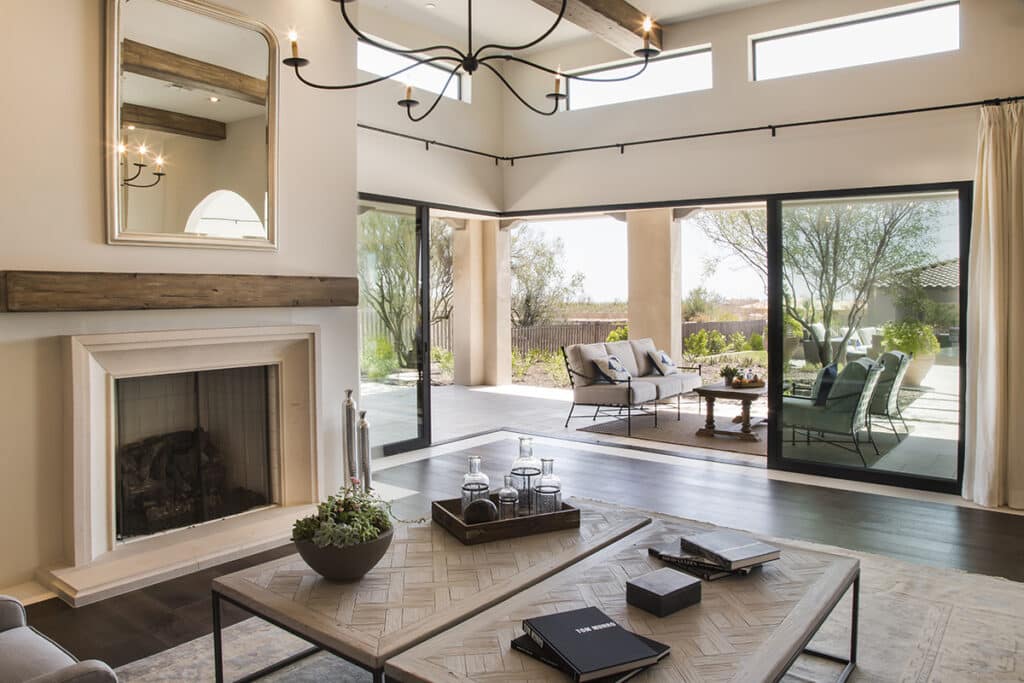 A cozy indoor living room transitions to an outdoor living area, uninterrupted by tall multi-slide glass doors.