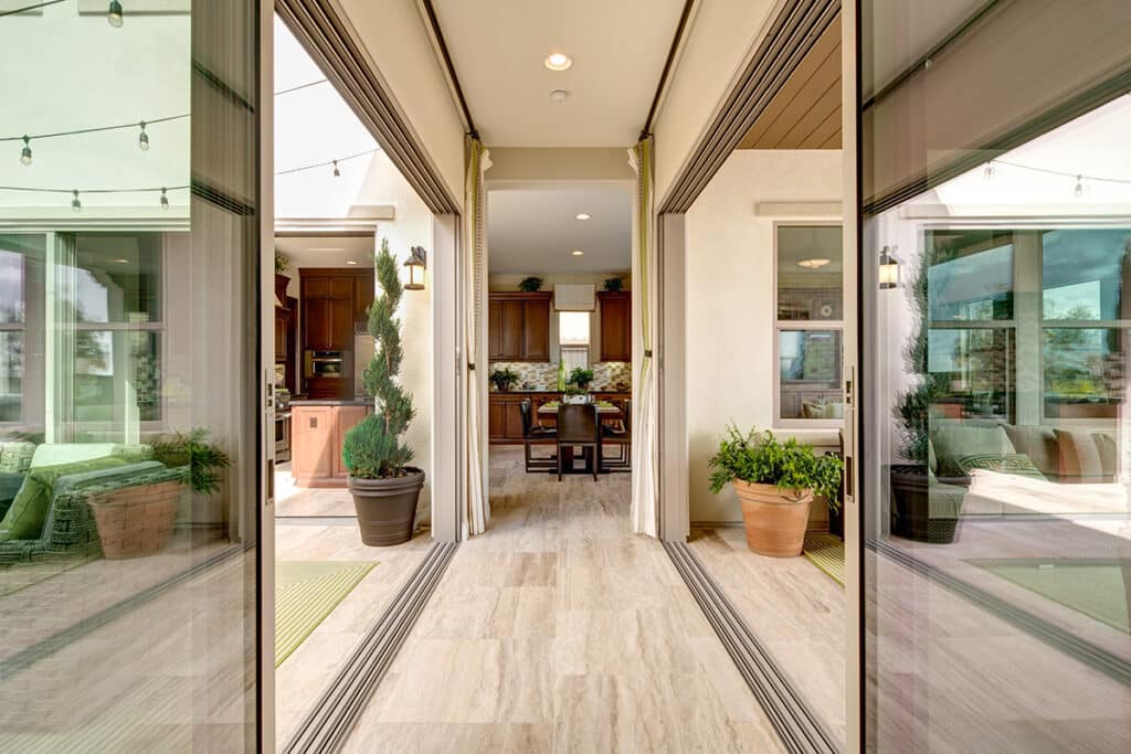 Two floor-to-ceiling multi-slide doors meet in a hallway to connect two outdoor living spaces.