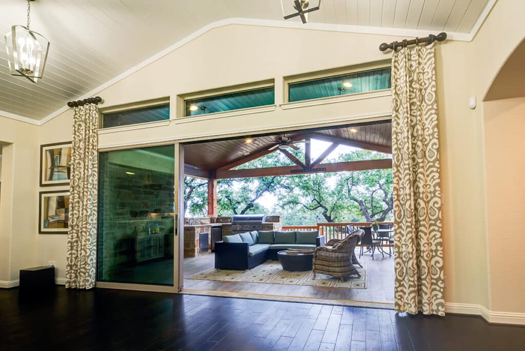 The inside of a home is opened to an outdoor living space through multi-slide glass doors.