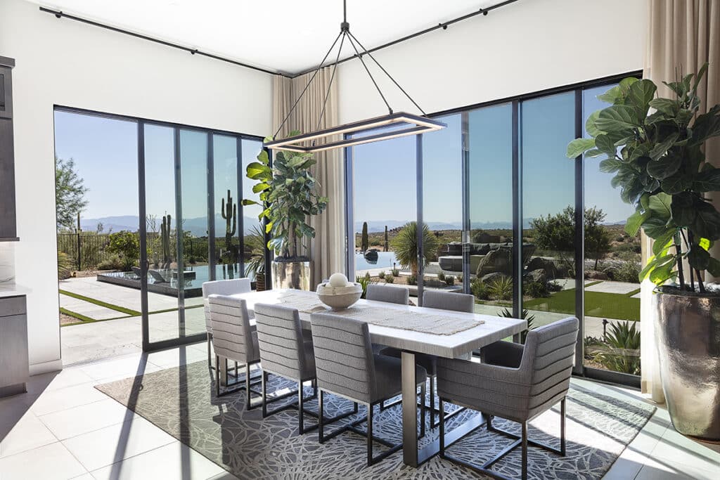 An indoor-outdoor dining space is separated by multi-slide glass doors leading to an outdoor infinity pool.