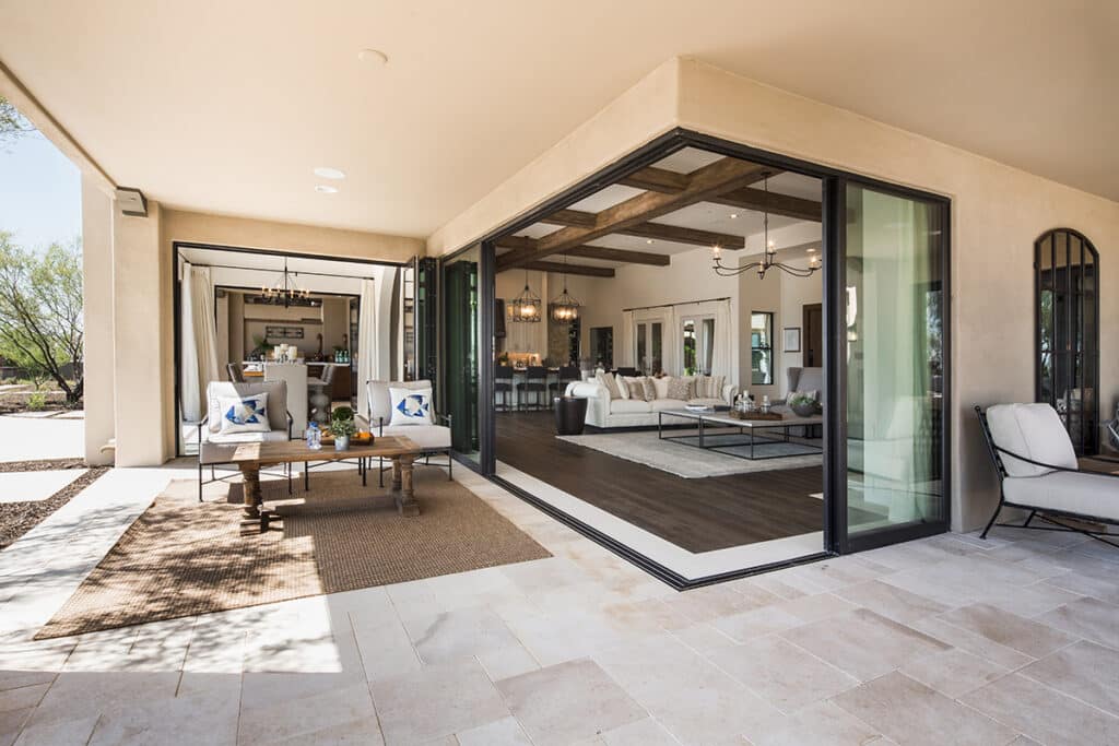 An outdoor living space seamlessly blends with the indoors through open multi-slide glass doors that meet at 90-degrees.