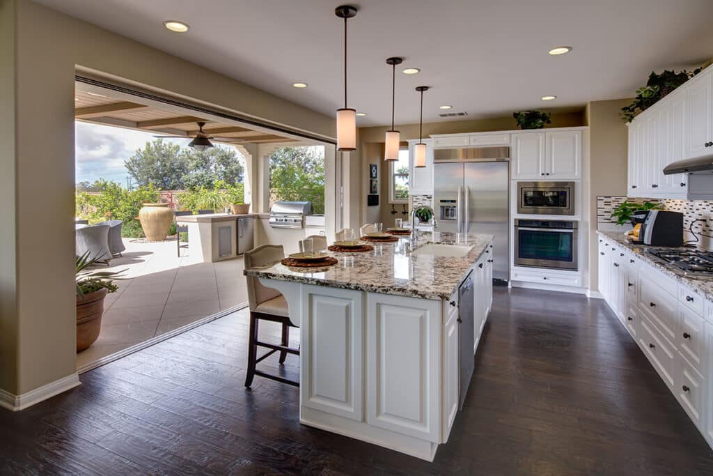 A pocketing multi-slide glass door is open, allowing an indoor kitchen to be expanded to the outdoors.