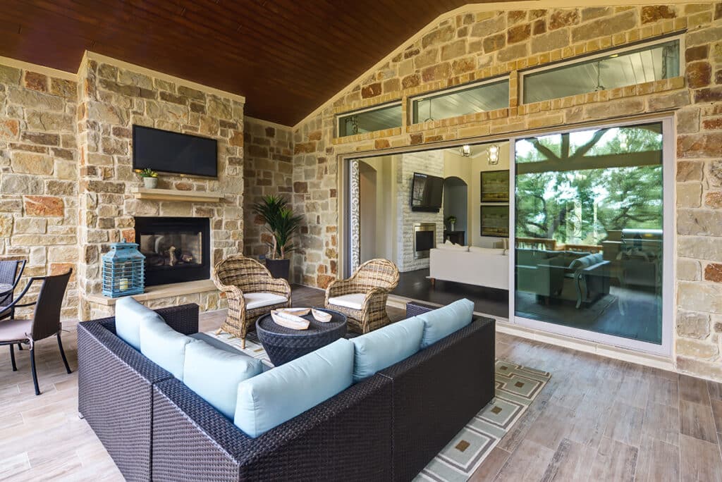 A cozy outdoor living area seamlessly transitions to the indoors via open multi-slide glass doors.