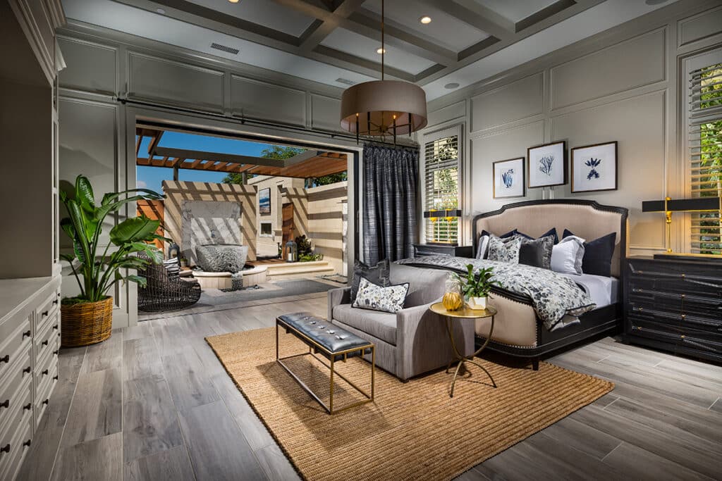A cozy, modern bedroom is connected to a private outdoor living space by an open multi-slide glass door.