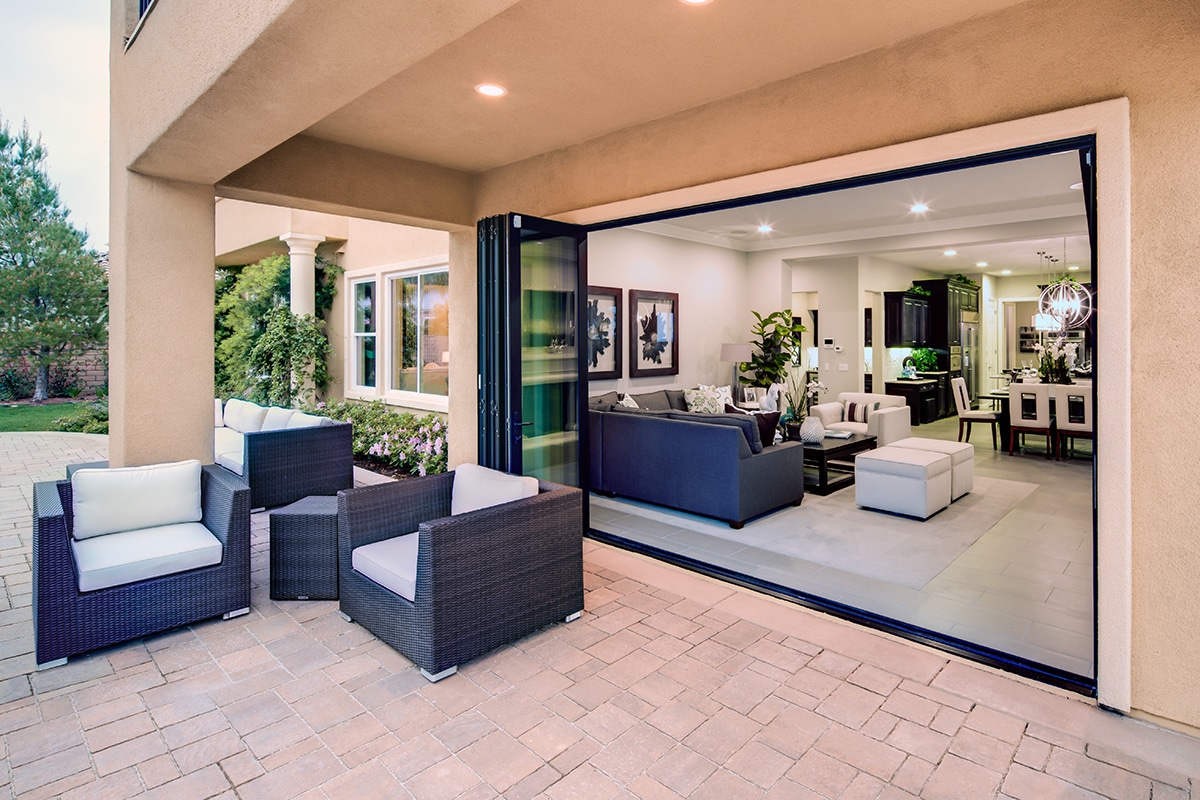 An open bi-fold door connects the living room to an outdoor seating area.