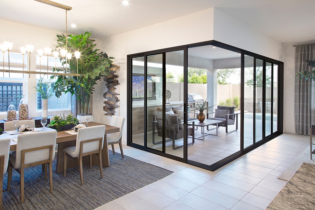 A half-open, 90-degree vinyl multi-slide door connects the dining room to the backyard patio.