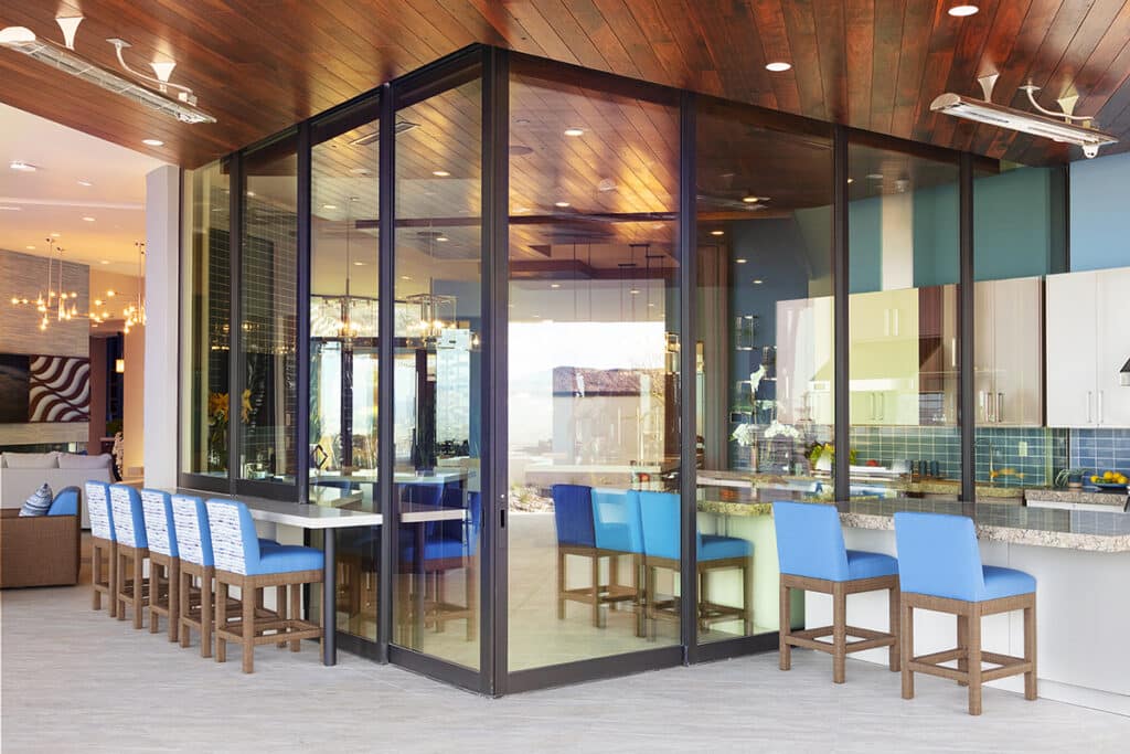 An outdoor view of a closed, 90-degree Series 7600 Multi-Slide Door surrounded by bar seating.