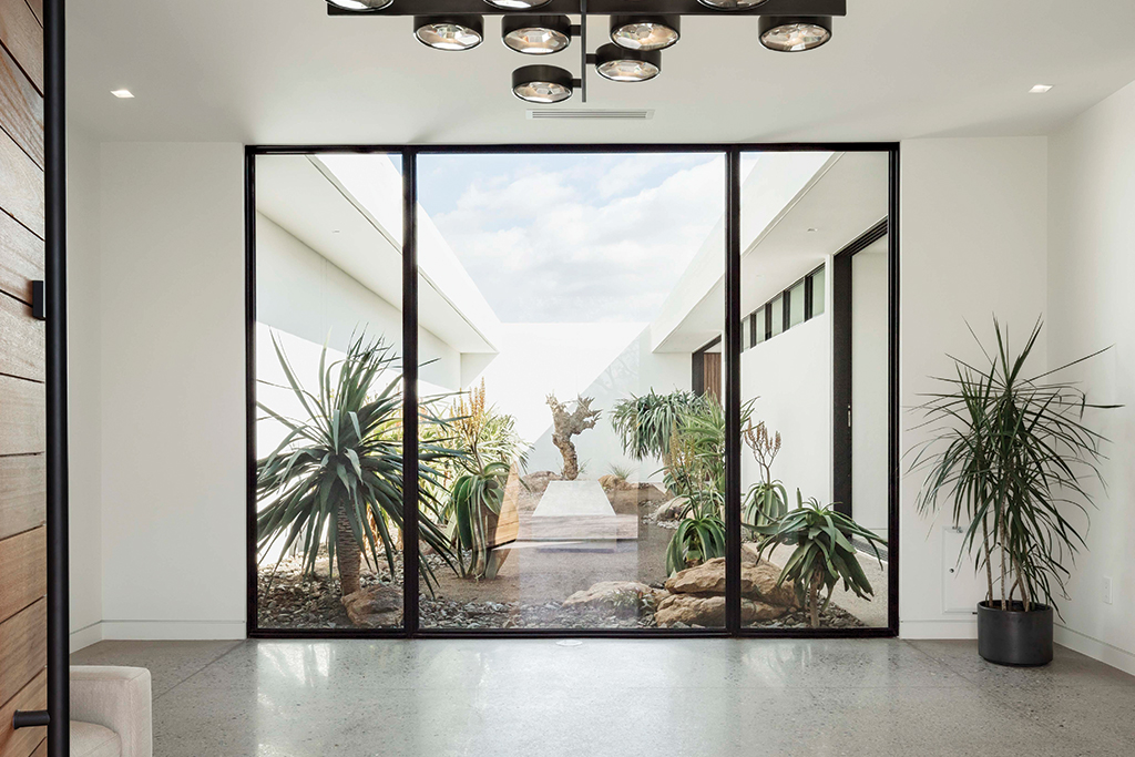 Three massive, fixed window panels frame the desert landscaping in the courtyard of this Arizona home.