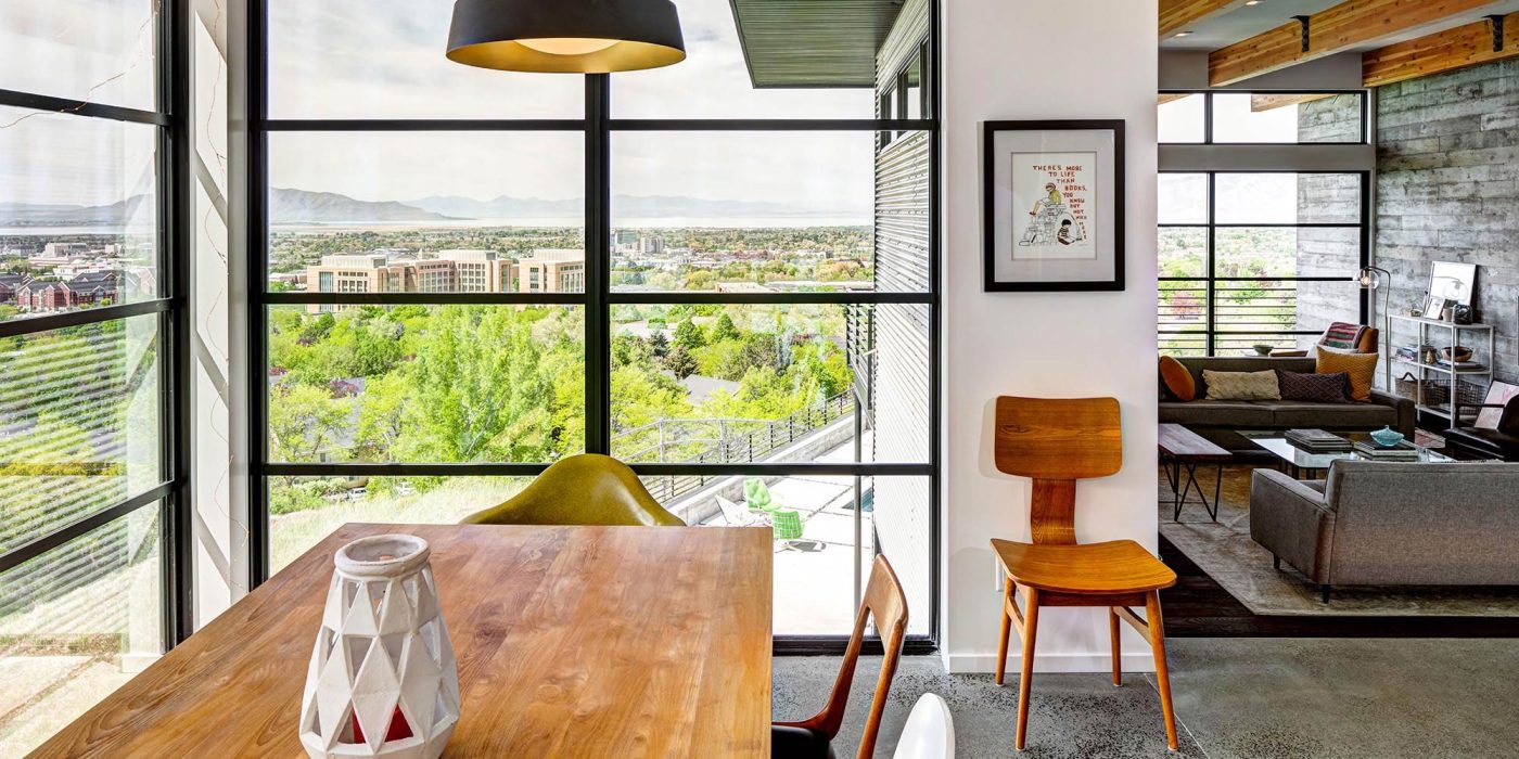 The window wall in this dining area provides beautiful views of the neighborhood with trees.