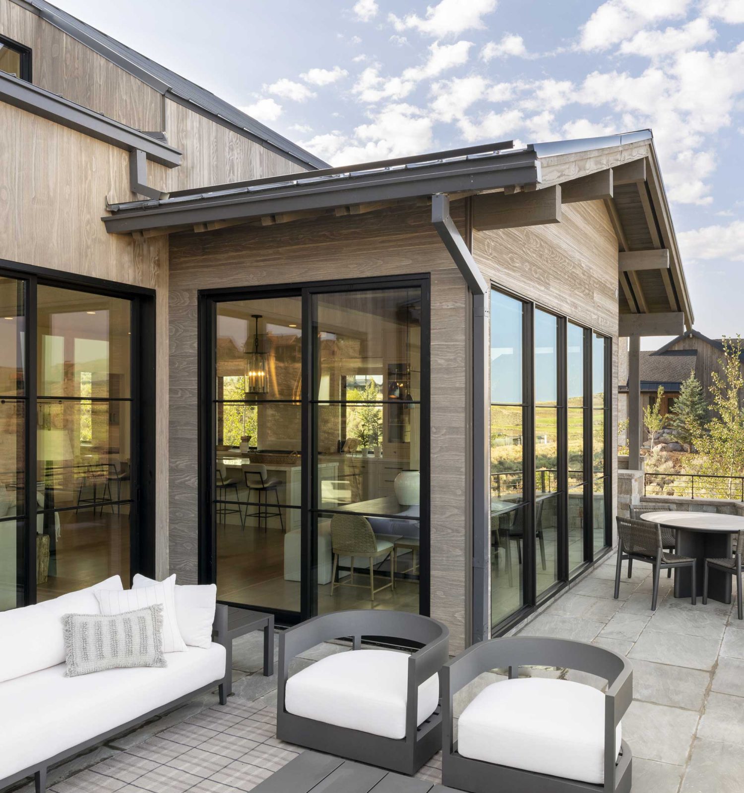 Large, divided light windows and multi-slide doors connect the patio to the great room.