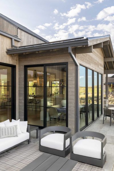 Large, divided light windows and multi-slide doors connect the patio to the great room.