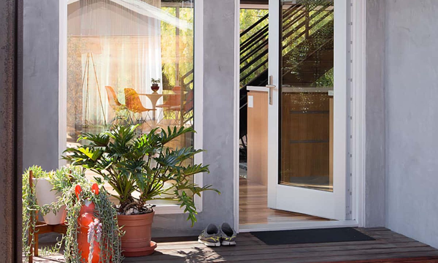 An open hinged door lends a modern aesthetic to the craftsman home next to a tall, fixed window.