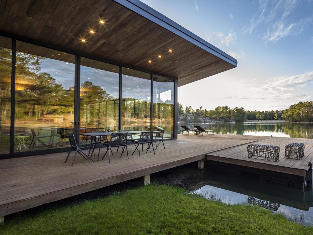 Floor-to-ceiling multi-slide doors completely open this home to the patio and lake the house sits on.