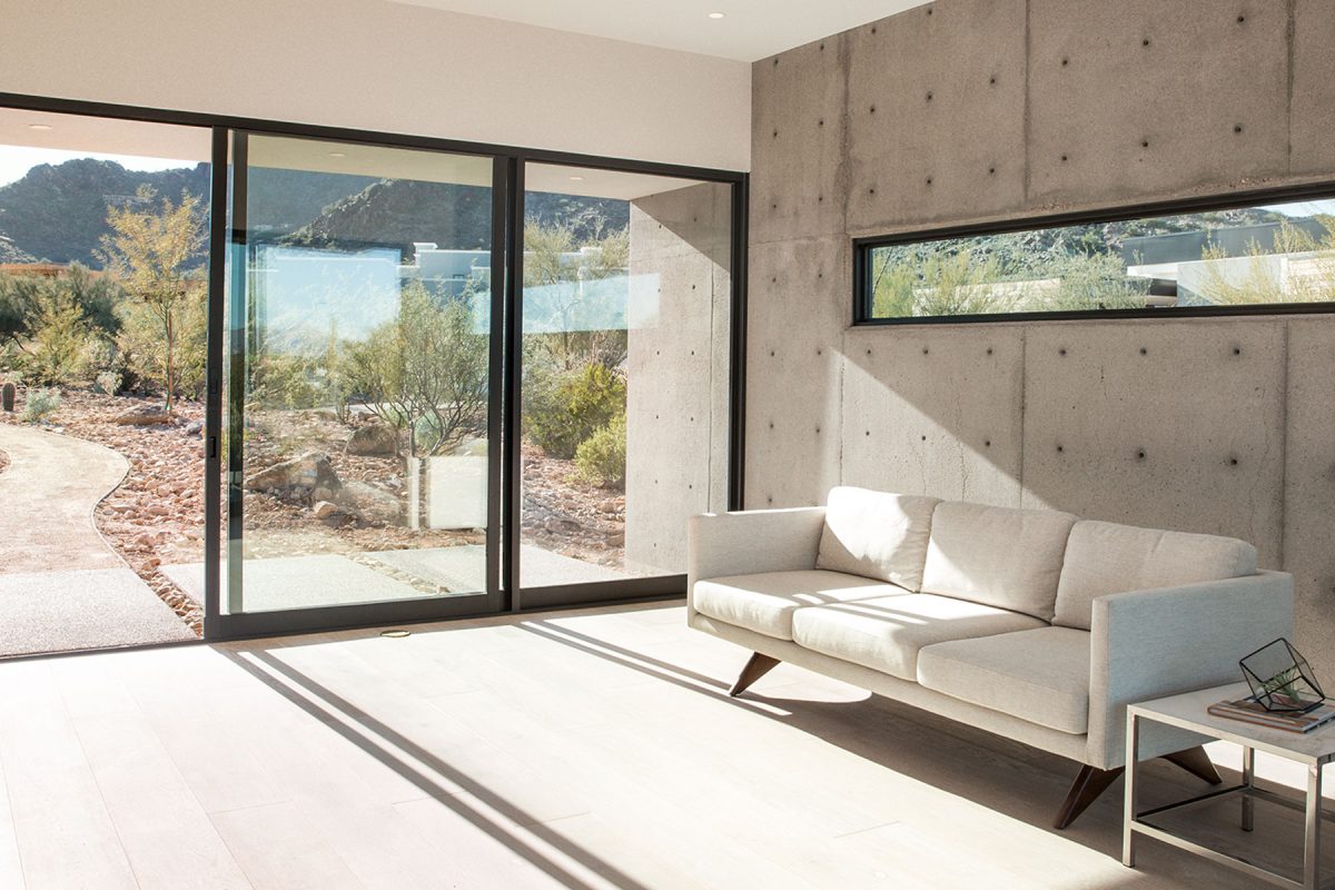 A room with an open multi-slide door leading to a pathway into the desert.
