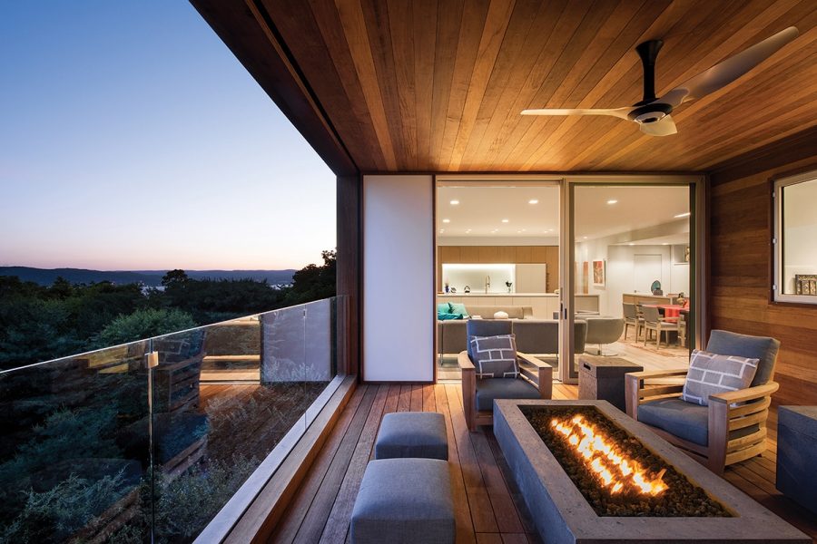 At dusk, a covered balcony with firepit has access to the kitchen through a sliding glass door.