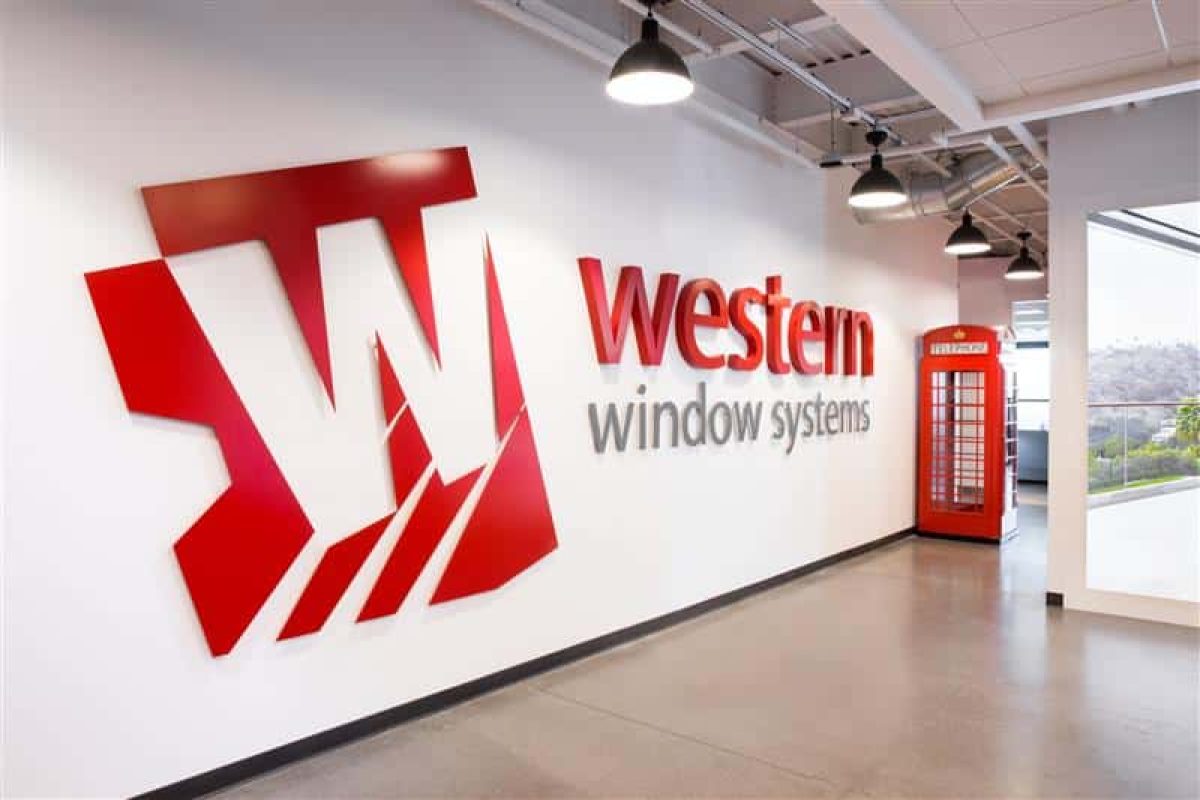 A three dimensional installation of the Western Window Systems logo is on a wall next to a British telephone booth.