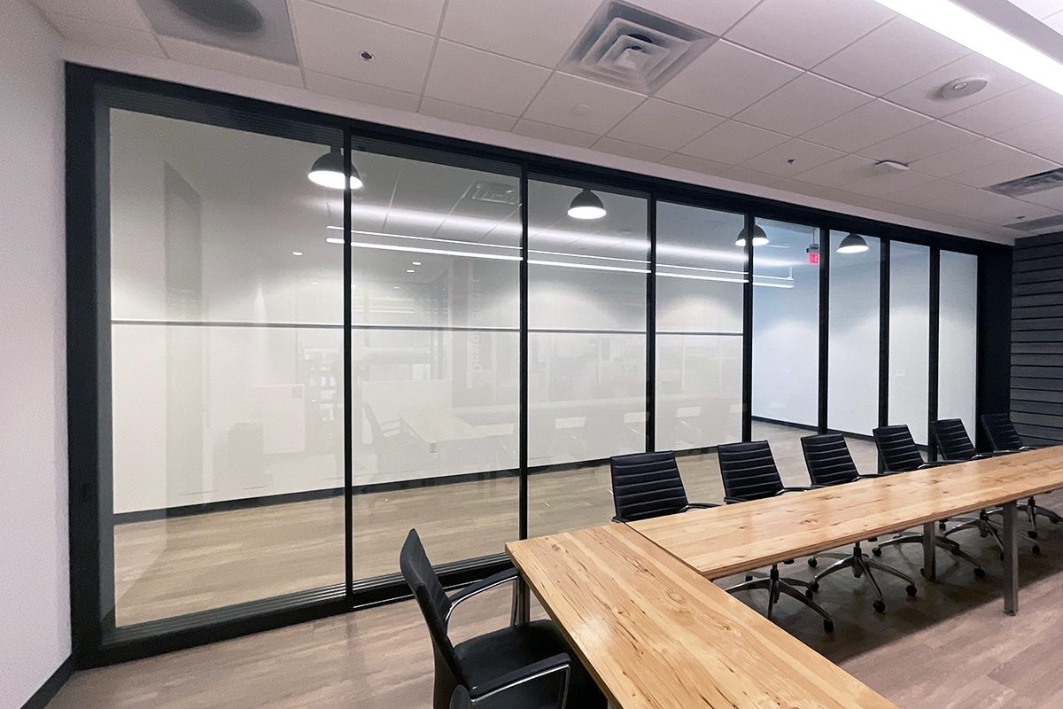 A photo of a conference room with a large glass wall with black frames.